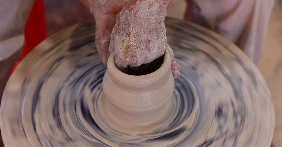 Hands centering clay on a spinning pottery wheel