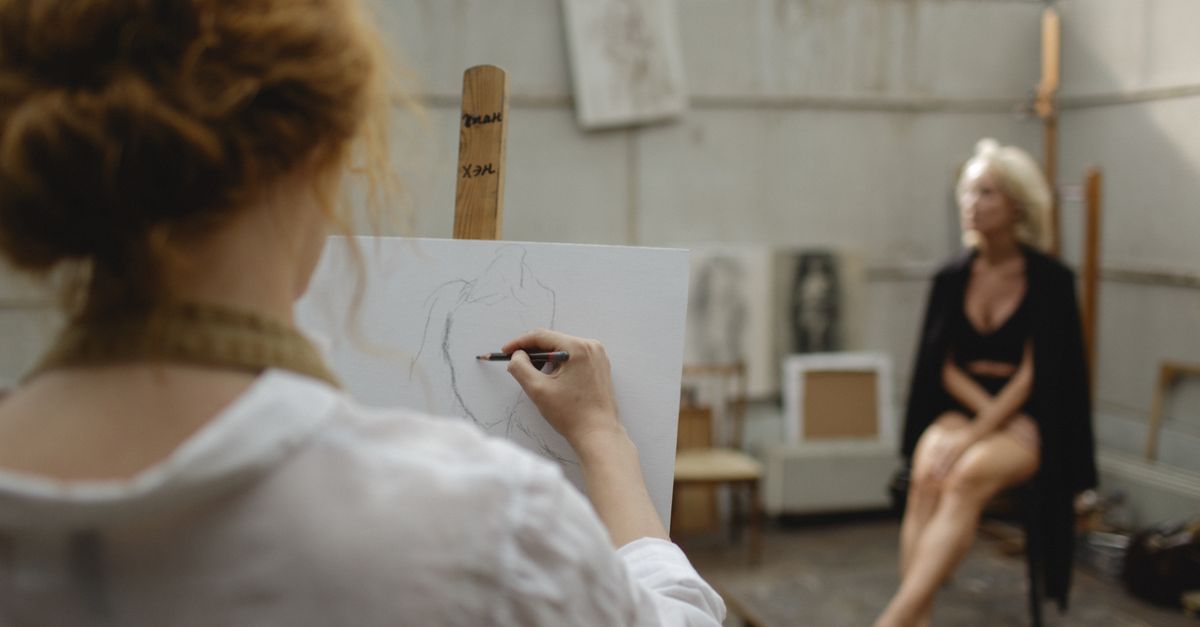 An artist sketching a model posing in an art studio