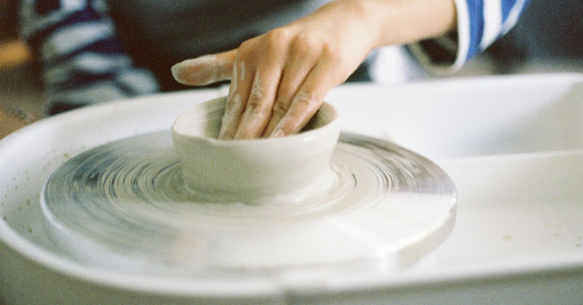 Hands shaping clay on a pottery wheel