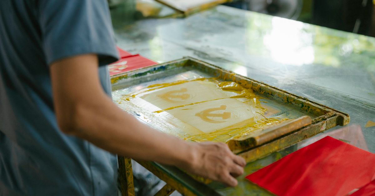 An artisan pulling a screen print in a workshop