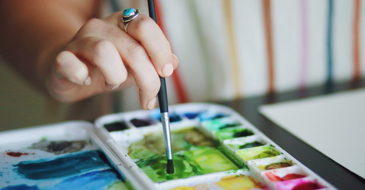 A hand holding a brush, working with watercolor
